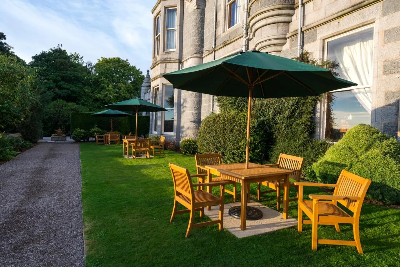 Wooden table and chairs with a green umbrella on the garden terrace
